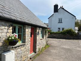 An outdoor area with a stone house and a nearby white house at Swallow Cottage near Cowbridge