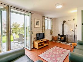 A living room with an open door and a television at Swallow Cottage near Cowbridge