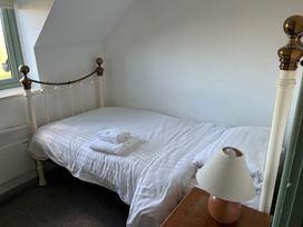 A bedroom with a bed and a lamp at Swallow Cottage near Cowbridge