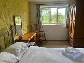 A bedroom with a bed, dresser, chair, and window at Wren Cottage in Cowbridge
