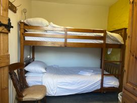 A bunk bed and a single bed in a bedroom at Wren Cottage Cowbridge