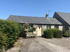 A cottage with a door and a bench at Wren Cottage in Cowbridge