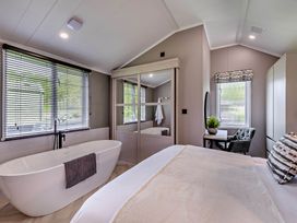 A bedroom featuring a bathtub and a workspace at Prion 1.0 Pet in Llandyrnog