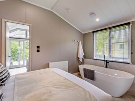 A bedroom with a bathtub and a window at Prion 1.0 Pet in Llandyrnog