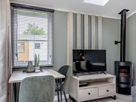 A living room with a table and a television at Prion 1.0 Pet in Llandyrnog