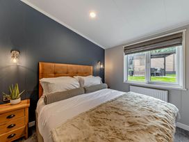 A bedroom with a bed and window overlooking a garden at Elwy 3.0 Pet Llandyrnog