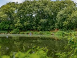 A pond with trees and benches at Pine Lodge Spa Carlton Miniott near Thirsk