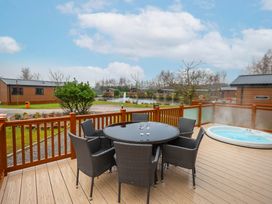 An outdoor space with a table and chairs plus a hot tub at Laurel Waterside Spa Carlton Miniott near Thirsk