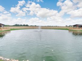 A pond with a fountain near a lodge at Laurel Waterside Spa Carlton Miniott near Thirsk