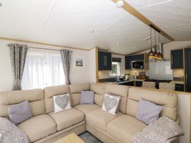 A living room with a sofa and kitchen area at 51 Calgarth Park in Troutbeck