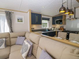 A living room with a sofa and kitchen area at 51 Calgarth Park in Troutbeck