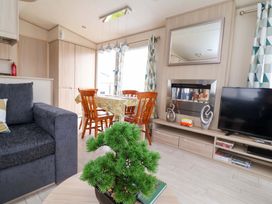A living room with a sofa, dining area, and television at 15 Cherry Tree Walk in Rhyl