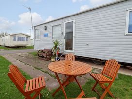 Outdoor area with a table and chairs in front of a caravan at 15 Cherry Tree walk Rhyl