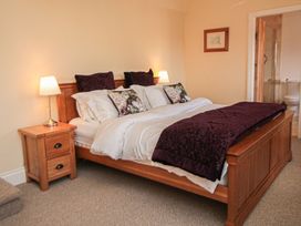A bedroom with a wooden bed and nightstand at Tuft House in Hovingham