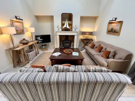 A living room with a sofa, coffee table, and lamp at The Chimney in Bamburgh