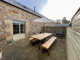 An outdoor patio with a table and benches at The Chimney in Bamburgh