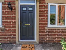 An entrance with a door, window, and doormat at Helmsley Cottage in Helmsley