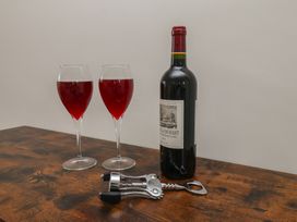 Two glasses of red wine with a bottle and corkscrew on a table at Helmsley Cottage in Helmsley