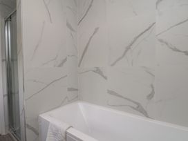 A bathroom with a bathtub and shower enclosure at Helmsley Cottage in Helmsley