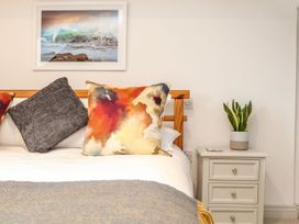 A bedroom with a bed, pillows, framed picture and a nightstand at Ty Bryn in Marazion
