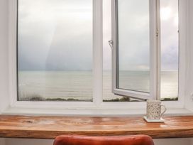 A view of the sea from a window with a cup on a table at Ty Bryn in Marazion