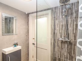 A bathroom with mirror, shower, sink and door at Ty Bryn in Marazion