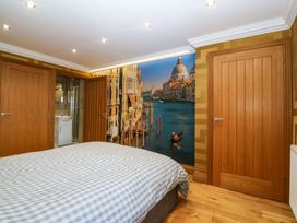 A bedroom with a bed and wooden doors at Apartment 1, Bryn Mel Manor in Menai Bridge