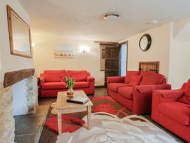 A living room with red sofas and a coffee table at Cider Cottage in Hawkchurch