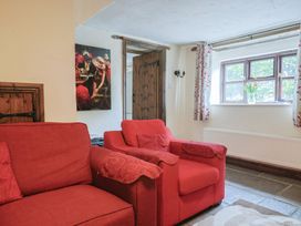 A living room with a red sofa and a window at Cider Cottage in Hawkchurch