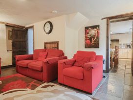 A living room with red sofas and a clock at Cider Cottage in Hawkchurch