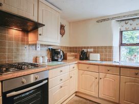 A kitchen with cabinets, oven, sink, and appliances at Cider Cottage in Hawkchurch