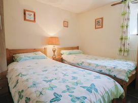 A bedroom with two single beds and a lamp at Cider Cottage in Hawkchurch