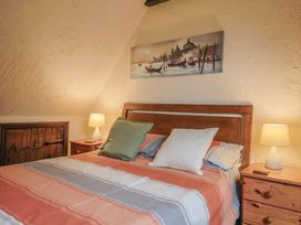 A bedroom with a bed, pillows, lamp, and painting at Cider Cottage in Hawkchurch