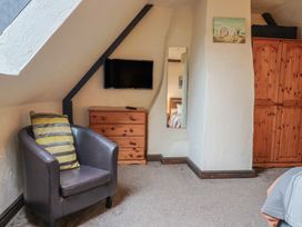 A bedroom with a television, armchair, chest of drawers, and wardrobe at Cider Cottage in Hawkchurch