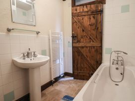 A bathroom with a sink, bathtub, and mirror at Cider Cottage in Hawkchurch