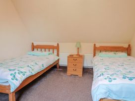 A bedroom with two beds and a nightstand at Cider Cottage in Hawkchurch