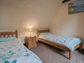 A bedroom with two beds and a nightstand at Cider Cottage in Hawkchurch
