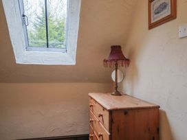 A bedroom with a window, chest of drawers, lamp, mirror, and picture at Cider Cottage in Hawkchurch