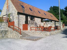 A stone house with a deck and seating area at Cider Cottage in Hawkchurch