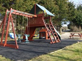 A playset with swings and a slide in an outdoor area at Cider Cottage in Hawkchurch
