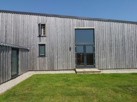 A building with a door and windows in a garden at Fieldstone Barn North Tawton
