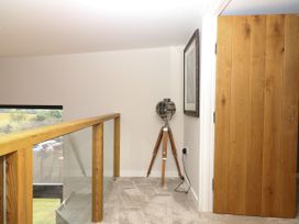 A landing area with a decorative lamp and a wooden door at Fieldstone Barn in North Tawton