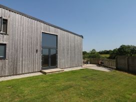 An outdoor area with a wooden building and patio at Fieldstone Barn in North Tawton