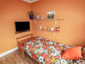 A bedroom with a bed and television at 1 Rosemount Garden Villas in Tenby