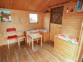 A garden room with a wooden table and benches at 1 Rosemount Garden Villas Tenby