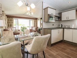 A living room with a dining area and kitchen at The Norfolk Nook 18 Castle Walk Burgh Castle