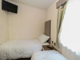 A bedroom with two beds and a television at The Norfolk Nook 18 Castle Walk Burgh Castle