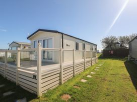 A caravan with a deck and grass area at Seaside Retreat in Selsey