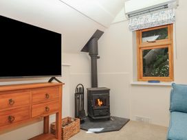A living room with a TV, wood stove, and window at The Mill Barn in Lustleigh
