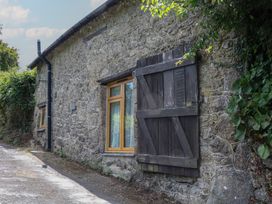 An exterior view of a stone cottage with a window and wooden shutters at The Mill Barn in Lustleigh